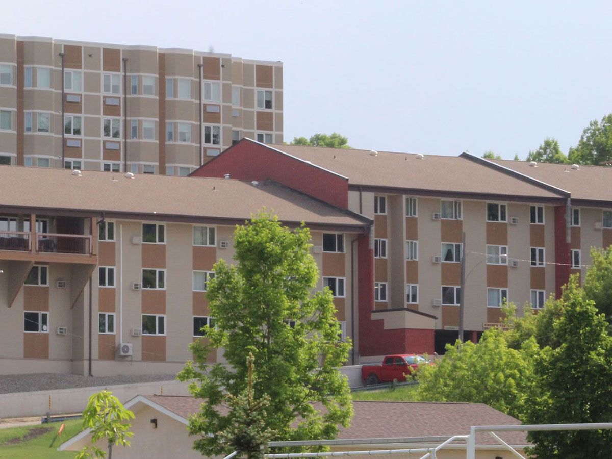Neepawa Kinsmen Kourts I building as seen front the north. Three storey building in tones of brown and beige.