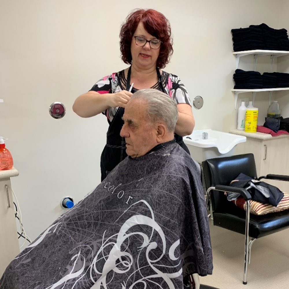 A male resident has his hair cut at the on-site hair salon at Kinsmen Kourts II in Neepawa, Manitoba